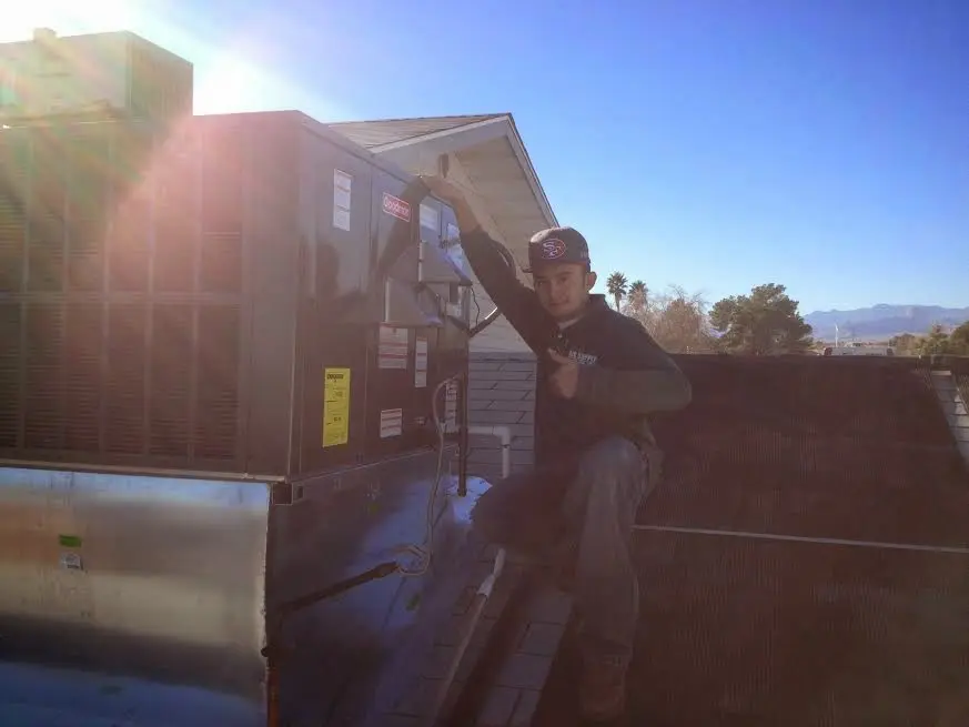 HVAC technician performing Air Duct Repair on a rooftop unit in Kingman