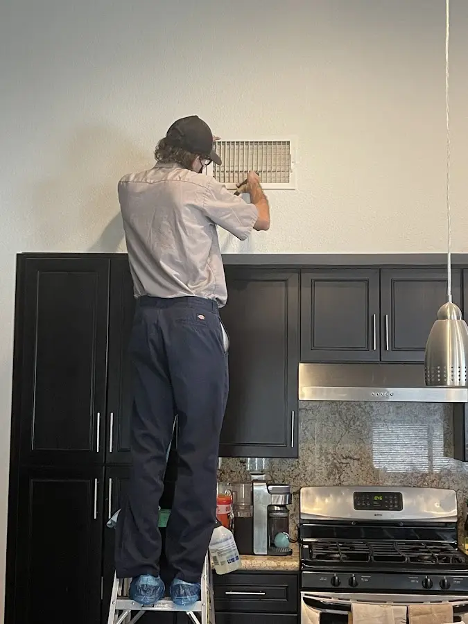 Technician inspecting an air vent during HVAC service in Kingman